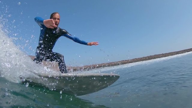SLOW MOTION, CLOSE UP, UNDERWATER: Awesome male surfer rides a large approaching barrel wave. Pro surfboarder carving waves in Lobos. Cinematic shot of fit male riding wave in the Canary Islands.