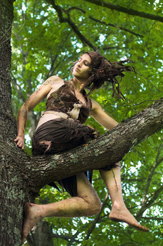 woman forest spirit sits on the branches of an old oak tree. costume and crown hand-made of felt