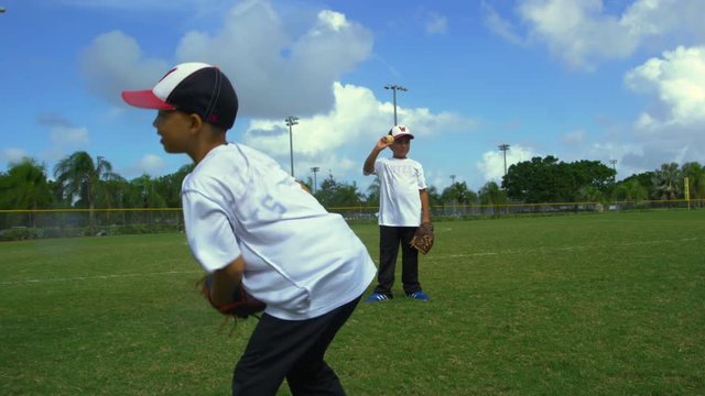 Slow motion of little boys catching and throwing balls during baseball practice