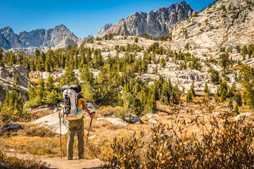 A solo backpacker pauses to take in the beautiful mountain peaks near Pee Wee Lake in the John Muir Wilderness, CA.