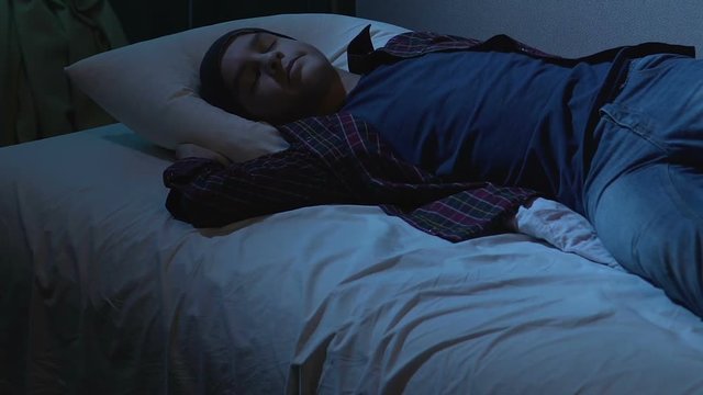 College student sleeping in cloth on bed after student party, dreams at night