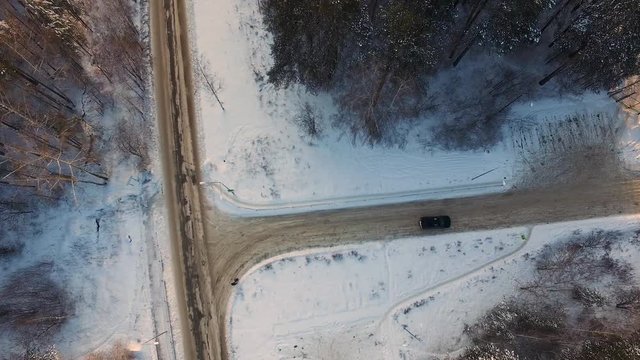 T-shape crossroad in snowbound forest at winter day. Aerial view. Footage. Car rides by crossroad in snow-covered forest at winter day. Aerial view.
