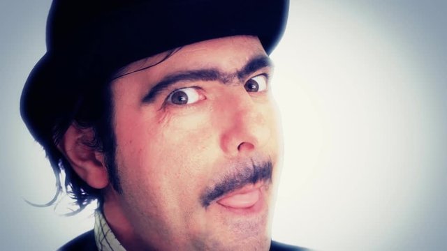 An ugly rich nerd with a hat and red gloves, looking at the camera with a depraved face, trying to catch the viewer with his hands. Funny comedy scene with a creepy character, extreme close-up shot.
