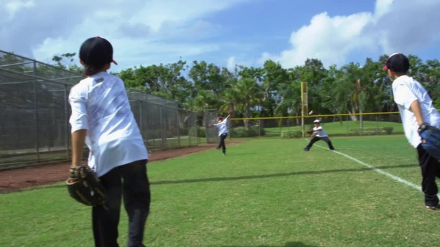 Slow motion of a group of kids throwing and catching balls at baseball park