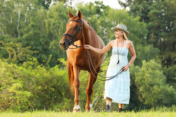 Woman lead her horse to parsure on summer afternoon