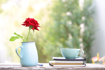 Teal cup and red rose in blue pot with notebook