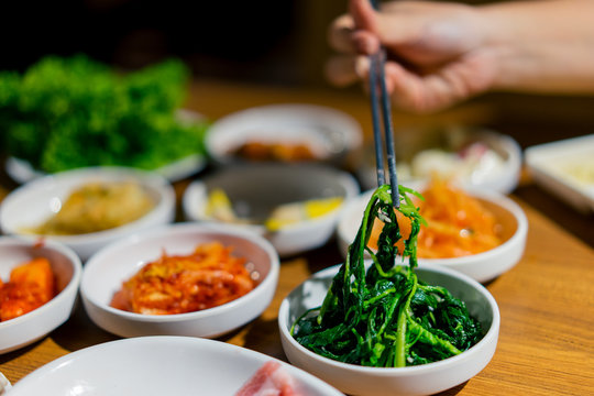 Woman Hand Holding Chopsticks For Eating Kimchi Salad In Restaurant. Korean Food Traditional Kimchi