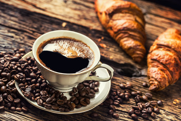 Coffee. Cup of coffee croissants and coffee beans. Vintage cup and old oak table