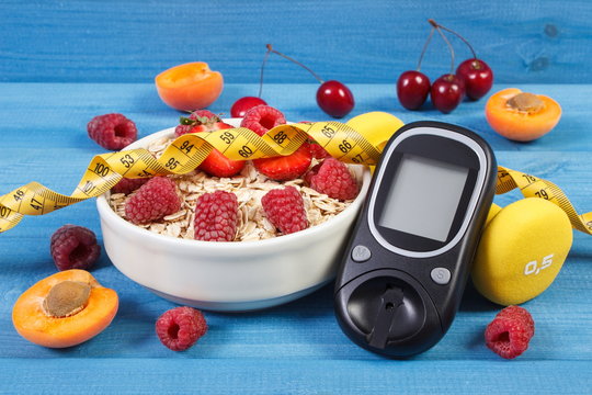 Glucose meter, fresh oatmeal with fruits, centimeter and dumbbells, concept of checking sugar level