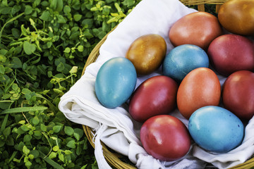 Easter eggs in a basket in green grass, empty copy space on the left side of image