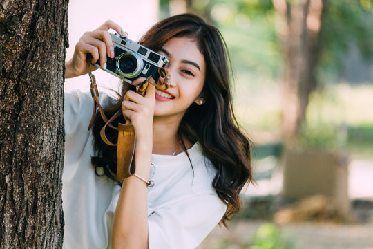 Asian woman taking picture with camera in park