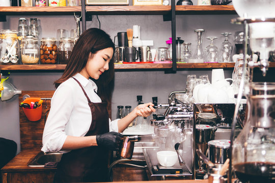 Women Barista using coffee machine for making coffee in the cafe