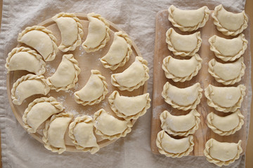 Dumplings raw on a wooden round board on a linen beige napkin. Traditional homemade food. traditional dish of Russian and Ukrainian cuisine