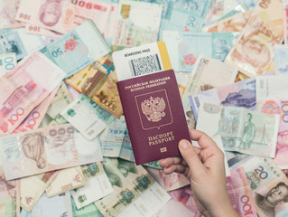 Female hand holding russian passport with boarding pass on Asia money background . Currency of Hong Kong, Indonesia, Malaysia, China, Thai, Singapore dollar. Travel and business concept 