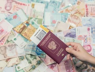 Female hand holding russian passport with boarding pass on Asia money background . Currency of Hong Kong, Indonesia, Malaysia, China, Thai, Singapore dollar. Travel and business concept 