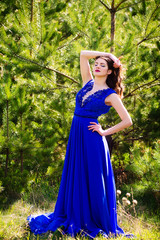 Beautiful fashion model in a dress in a green park in the summer . Blue dress.