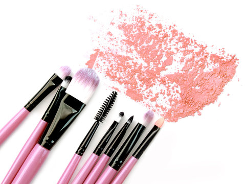 Various makeup brushes crushed powder isolated over white background