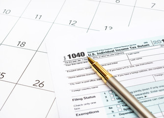Pen with tax forms on the calendar.