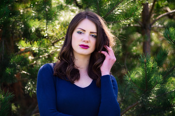 Beautiful fashion model in a dress in a green park in the summer . Blue dress.