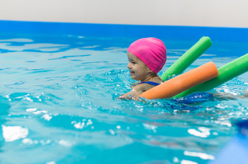 A little girl of European appearance floating in the pool on inflatable toy