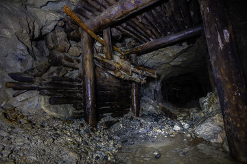 Fototapeta premium Underground abandoned gold ore mine shaft tunnel gallery with wooden timbering