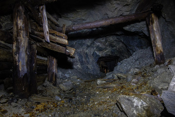 Underground abandoned gold ore mine shaft tunnel gallery with wooden timbering