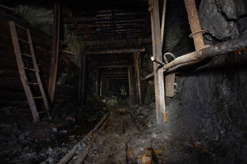 Underground abandoned gold ore mine shaft tunnel gallery with rails railway