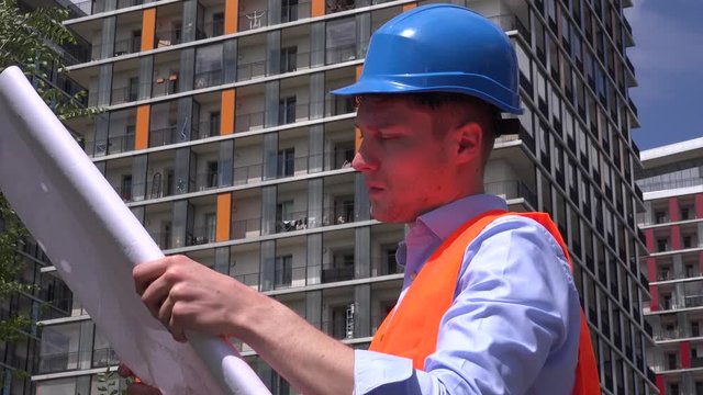 Attractive man builder constructor reading analyzing blueprints engineer smiling