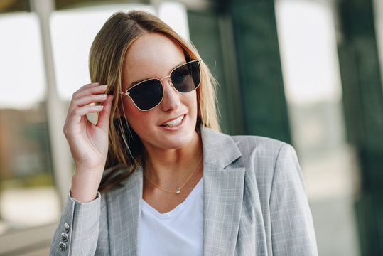 Beautiful young blonde woman with sunglasses in urban background.