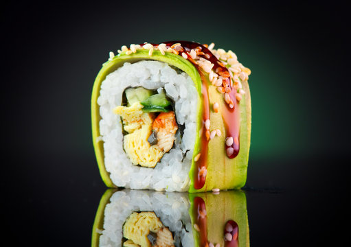 Sushi roll over black background. Sushi roll with eel, tofu, vegetables and avocado closeup. Japanese food 