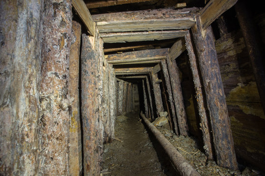 Underground abandoned ore mine shaft tunnel gallery with wooden timbering