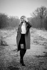 Woman walks near airport in dreaming mood at early spring, wearing wool oversize stylish coat 