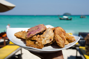 Fried banana in plate with woman hand ,seaside
