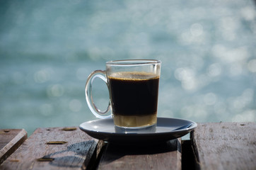 Close up Coffee cup on wood table and view of tropical beach.