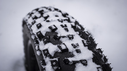 Close up shot of the tread on a fat mountain bike tire in snow .