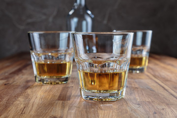 three glasses of whiskey on the oak surface of the table