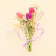 bouquet of pink and white tulips over pastel wooden background. Top view.