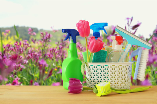 Spring cleaning concept with supplies on wooden table.