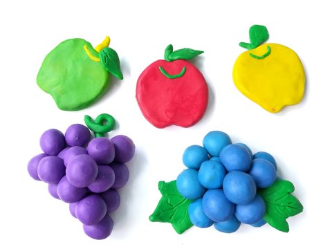 Colorful clay plasticine made are delicious fruits on white background, cute variety apples grasses blueberry dough