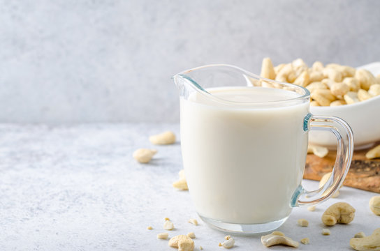 Cashew milk in a milk pitcher with cashew nuts