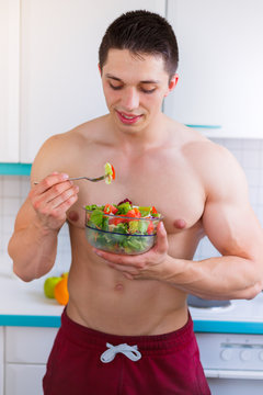 Junger Mann isst essen Salat Bodybuilding Bodybuilder gesunde Ernährung Hochformat vegan