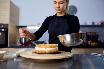 A confectioner woman makes  cake in the kitchen in a pastry shop.