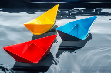 Papierschiffe gefaltet schwimmen in bunten Farben auf dem Wasser