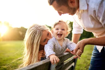 Fotobehang Happy family in a park in summer autumn. Mother, father and baby play in nature in the rays of sunset. © Studio Romantic