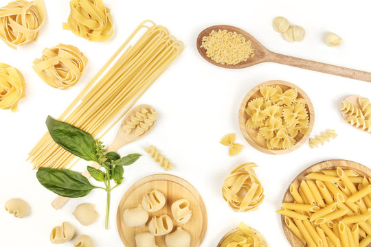 Overhead photo of different types of pasta with basil on white with copy space