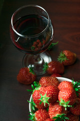 A glass of red wine and strawberries