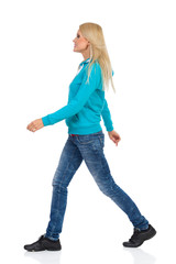 Walking Woman In Jeans And Turquoise Blouse. Side View.