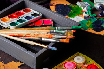 Paints for drawing and brush on a background in a composition