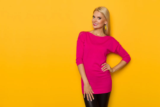 Beautiful Blond Woman In Pink Sweater Is Smiling And Looking At Camera