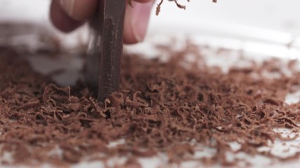 Closeup slow motion of making dark chocolate shavings with knife
